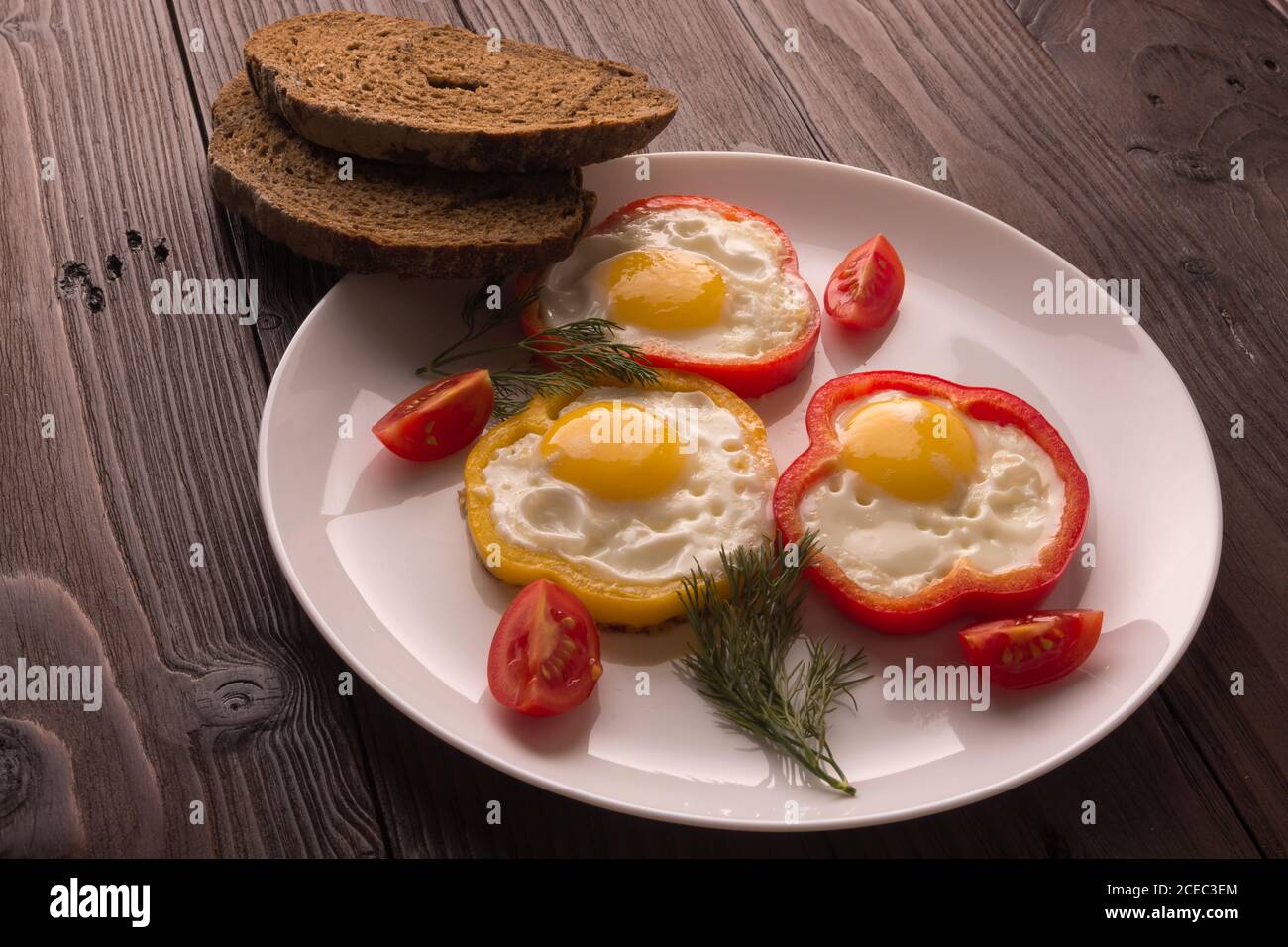 Scrambled eggs fried in rings of Bulgarian pepper with tomatoes and herbs. Stock Photo