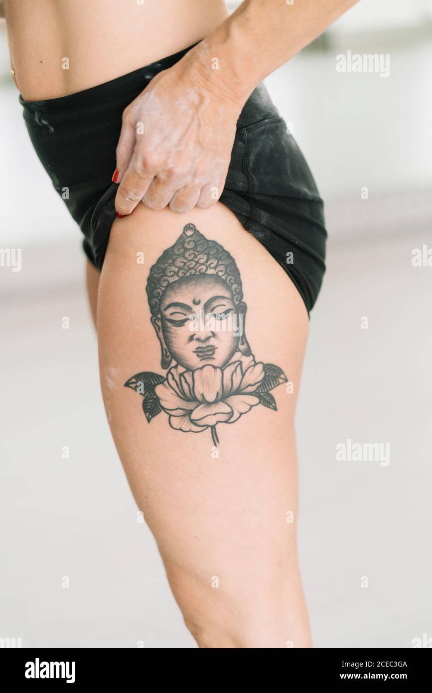 Side view of crop female athlete showing Buddha tattoo on leg while training in gym Stock Photo - Alamy