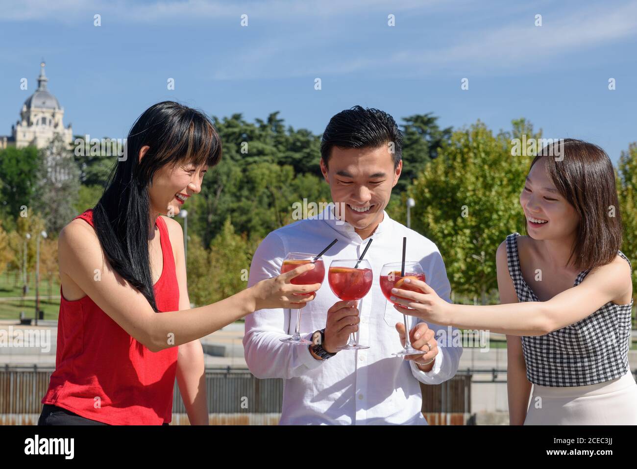 Asian tourists clinking glasses on street Stock Photo
