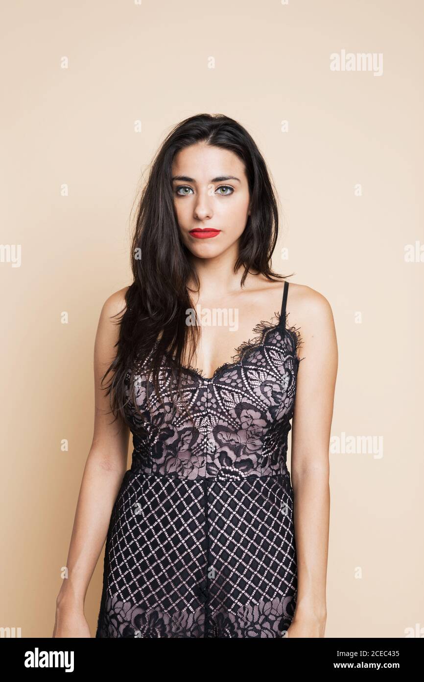 Beautiful young brunette lady in nice black gown looking at camera on pink background Stock Photo