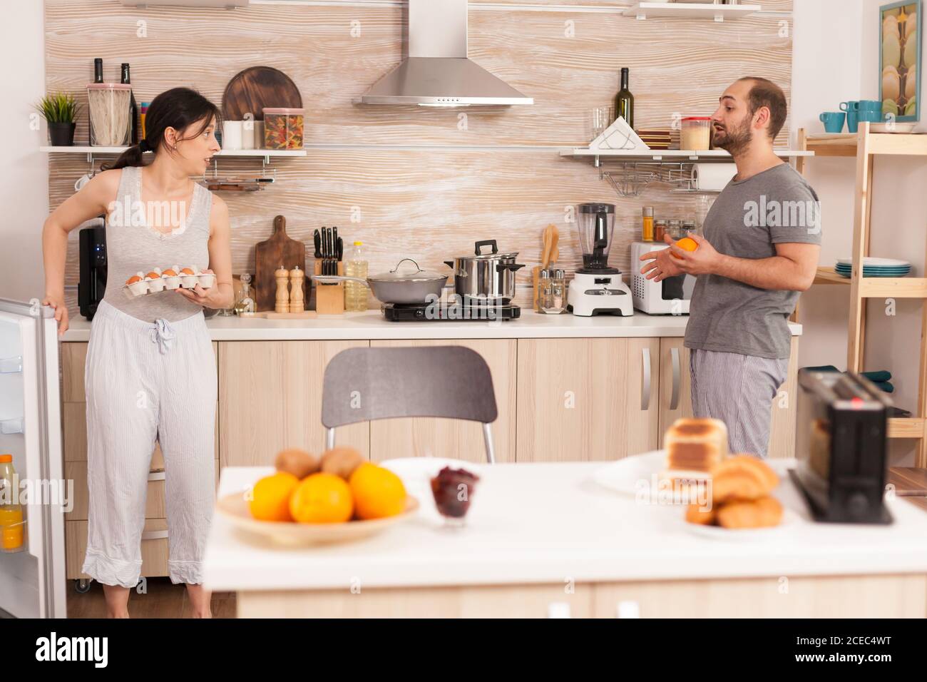 https://c8.alamy.com/comp/2CEC4WT/housewife-picking-up-eggs-from-fridge-wearing-pajamas-to-cook-breakfast-husband-having-a-conversation-with-wife-while-she-is-cooking-the-morning-meal-2CEC4WT.jpg