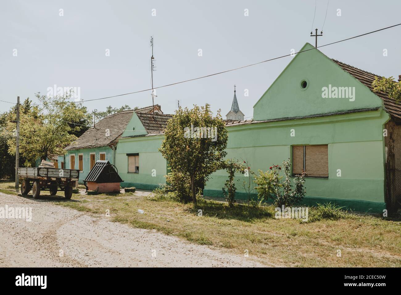 The view of an old gravel street with green rural building in Serbian village called Češko Selo near the Bela Cerkva in part of Serbia called Banat Stock Photo