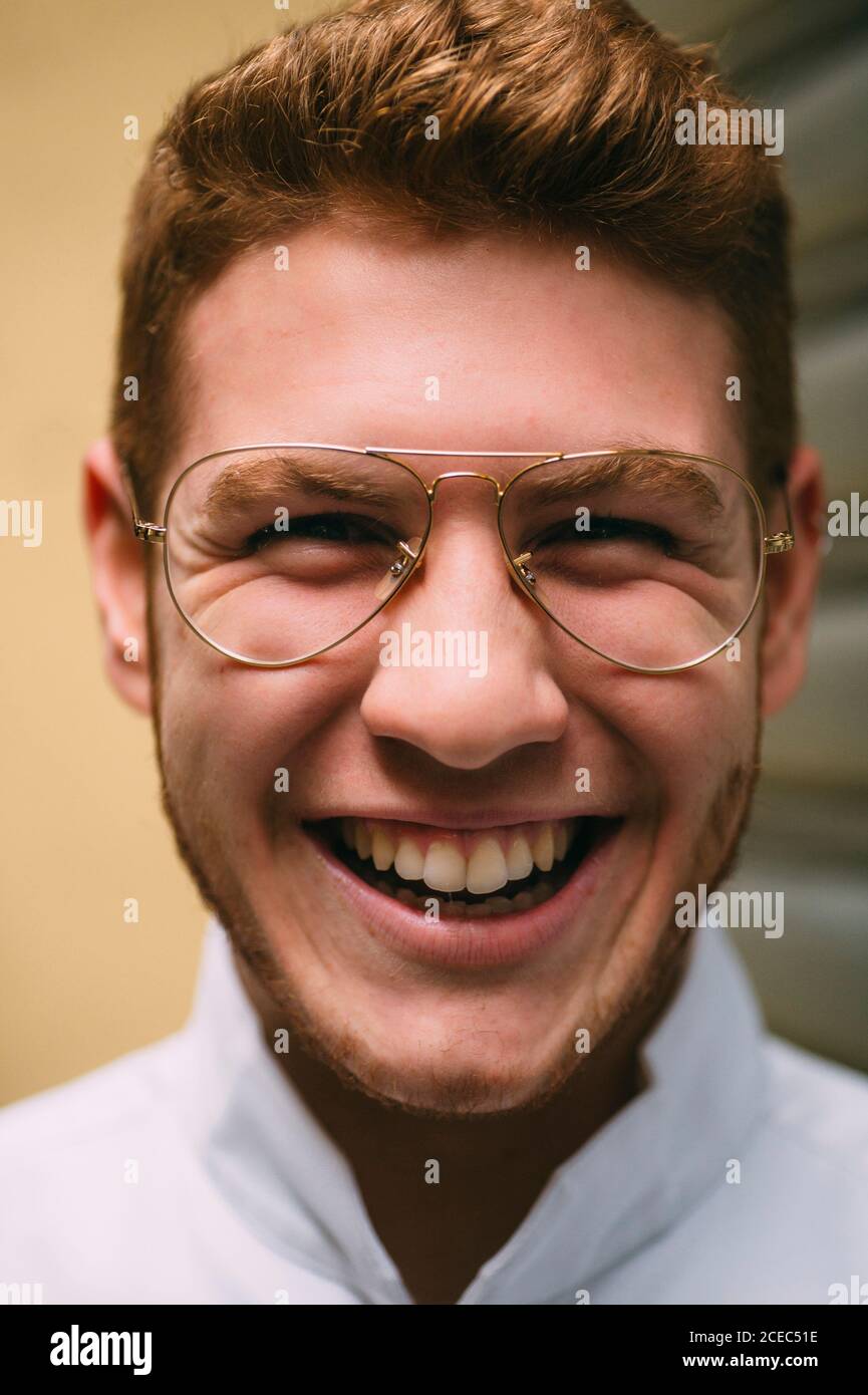 Close-up of cheerful bright redhead man in stylish glasses looking at the camera crazily with excitement. Stock Photo
