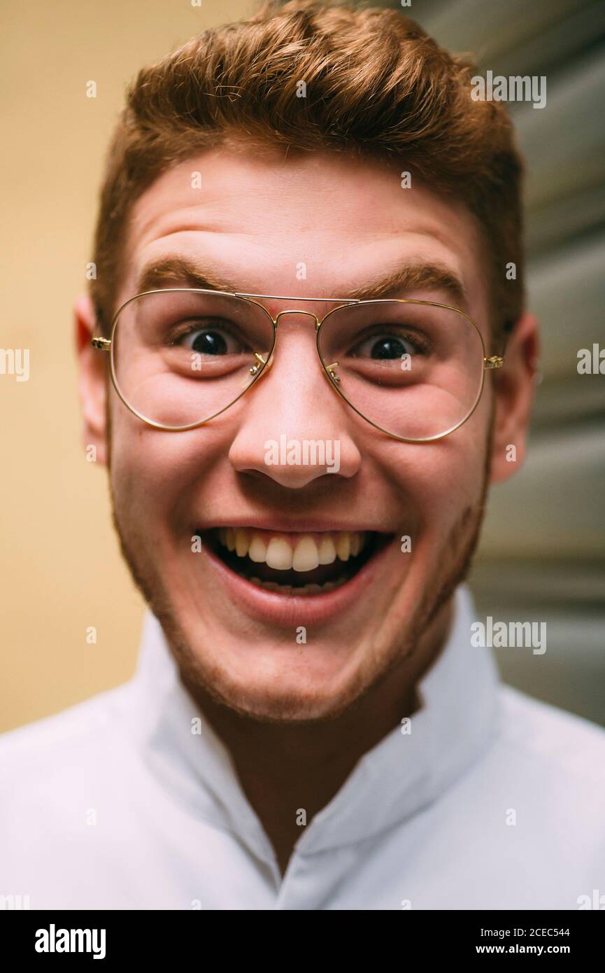 Close-up of cheerful bright redhead man in stylish glasses looking at the camera crazily with excitement. Stock Photo