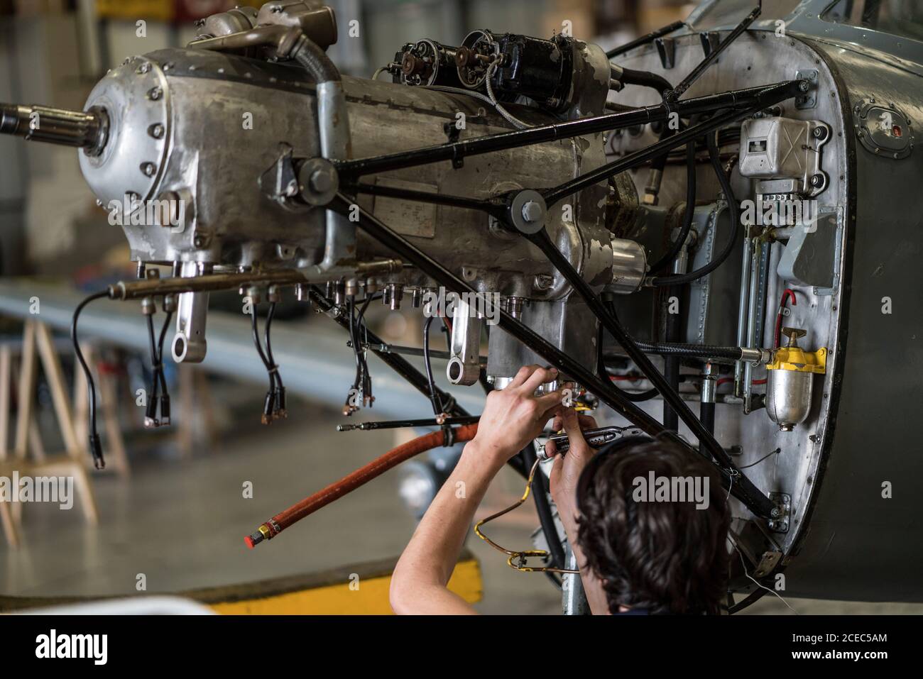 Crop hands of aircraft mechanic fixing engine of small airplane in hangar Stock Photo