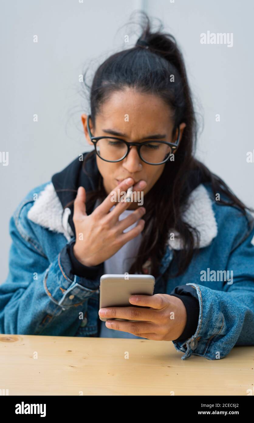 Young Woman smoking cigarette and browsing smartphone Stock Photo