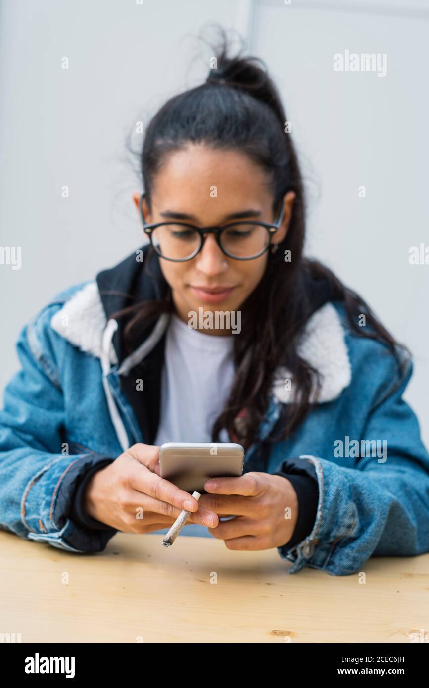 Young Woman smoking cigarette and browsing smartphone Stock Photo