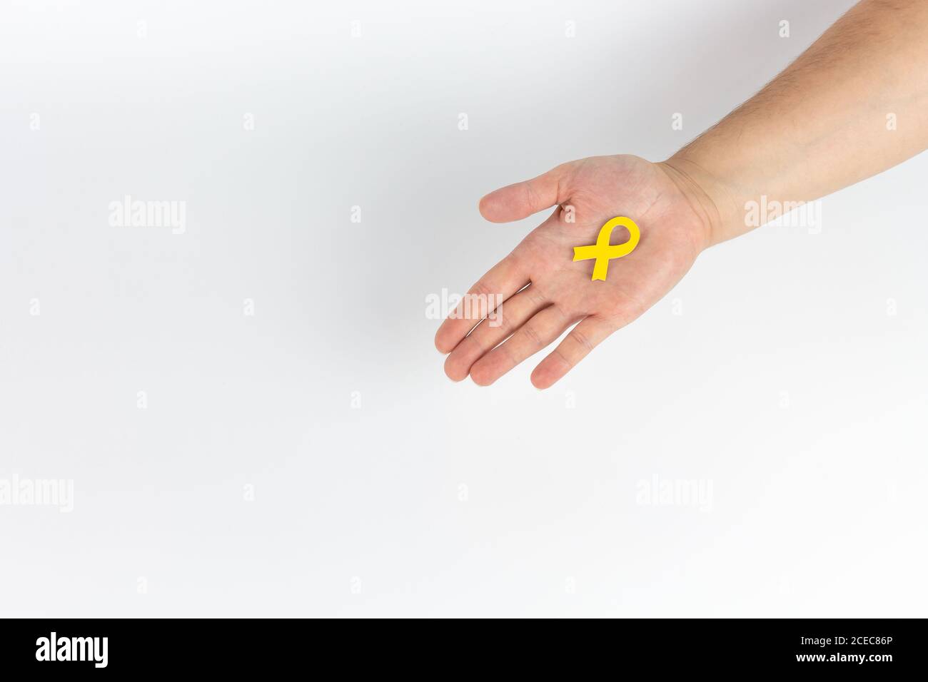 View of a hand holding a small yellow wooden bow on a white background Stock Photo