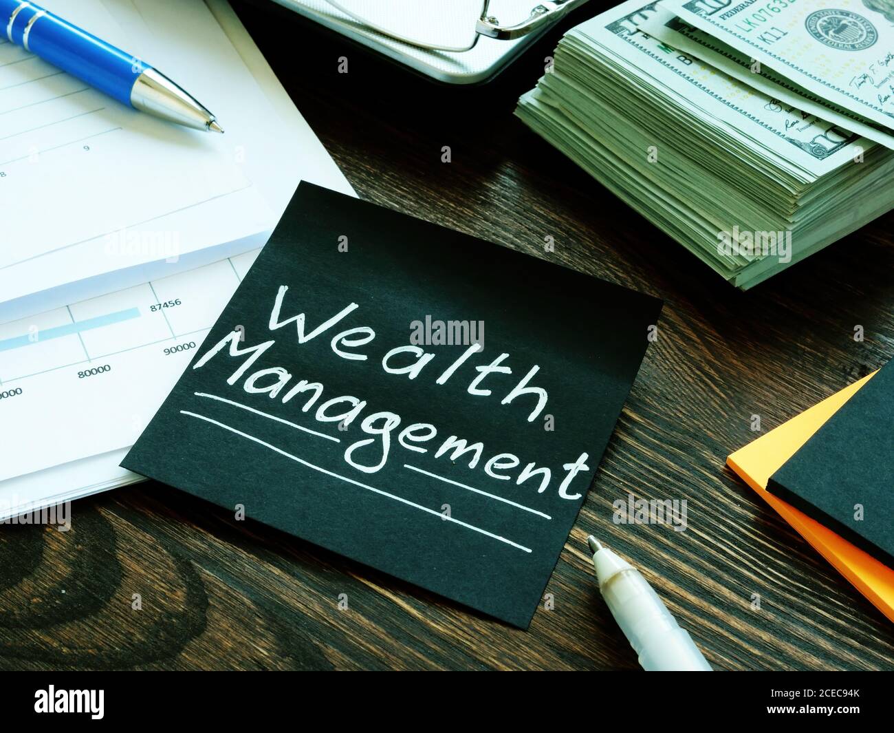 Stack of money and wealth management sign on the black sheet. Stock Photo
