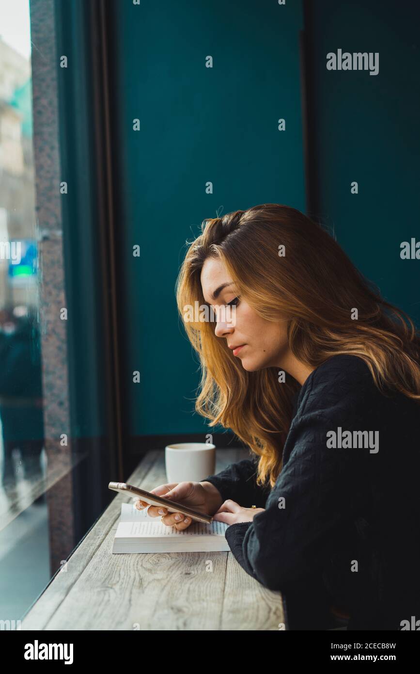 Woman using smartphone in cafe Stock Photo