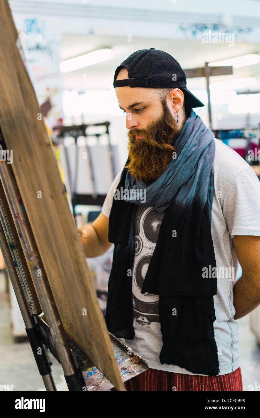 Bearded man drawing on easel Stock Photo - Alamy