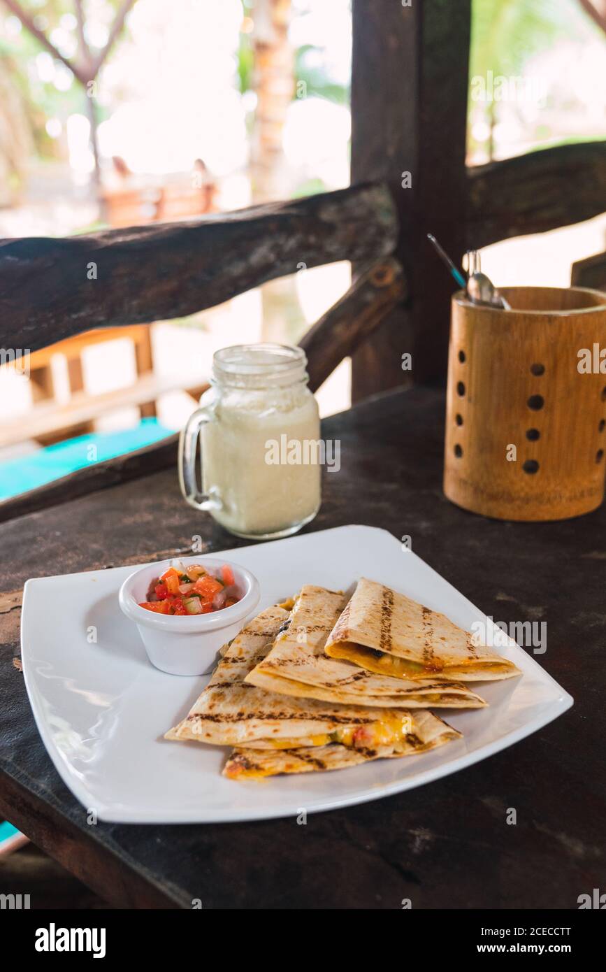 White plate with served grilled quesadilla pieces and salsa sauce on table Stock Photo
