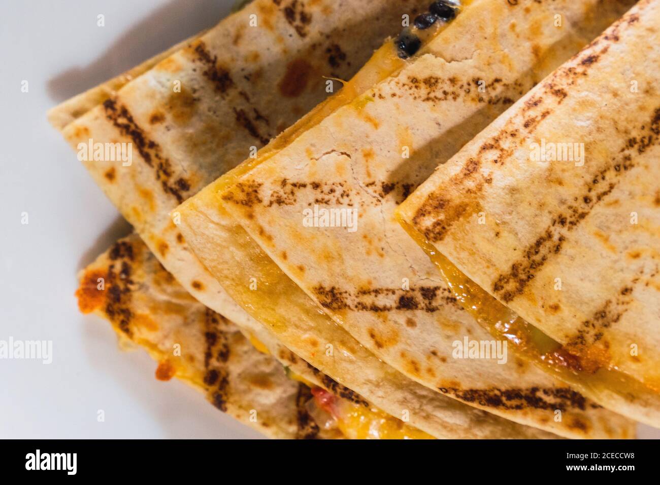 White plate with served grilled quesadilla pieces and salsa sauce on table Stock Photo