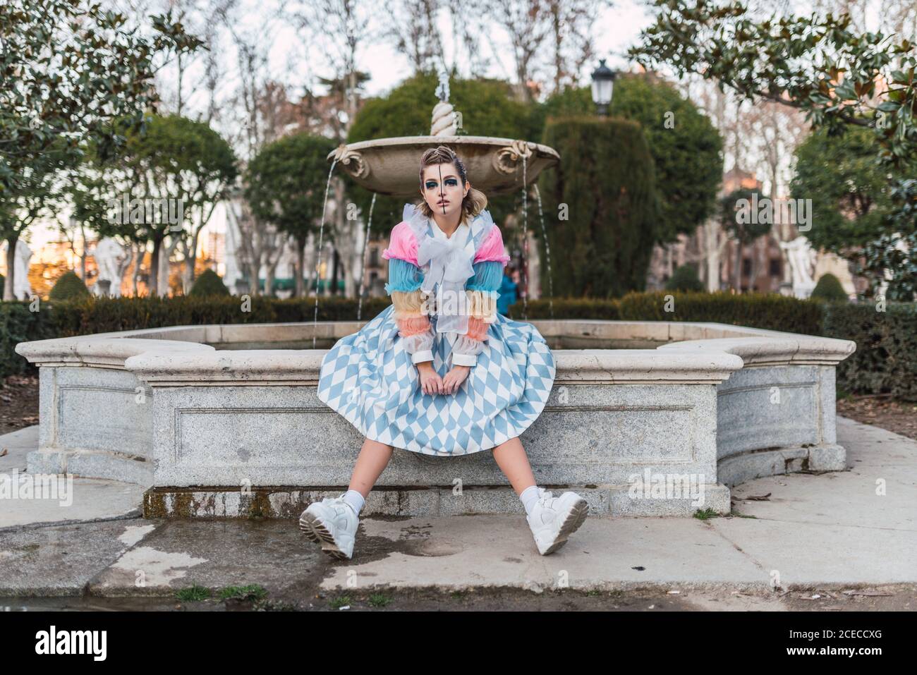 young Woman in theatrical costumes acting near old fountain in beautiful park Stock Photo