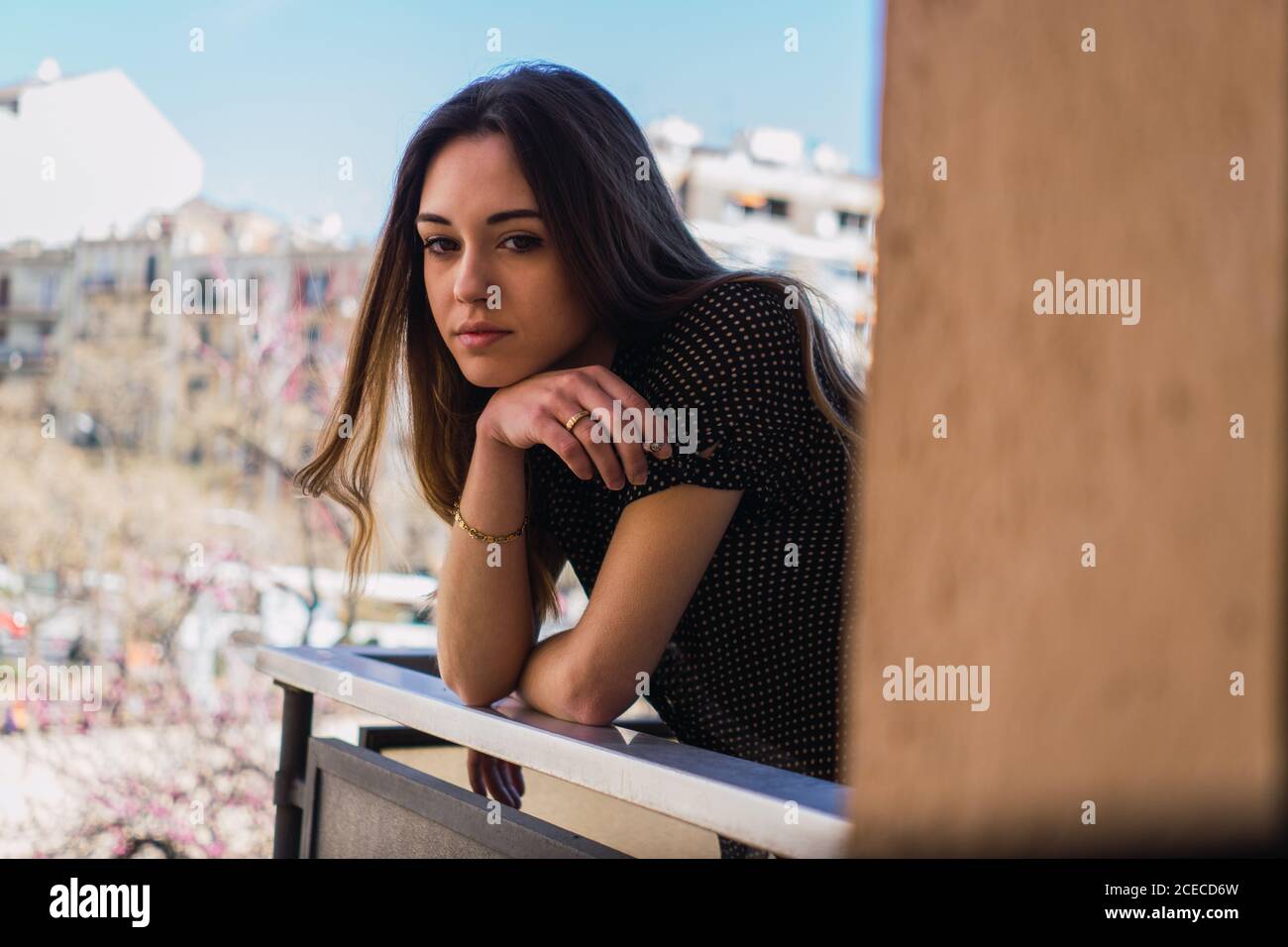 Dreamy young brunette Woman standing on balcony and looking away. Stock Photo