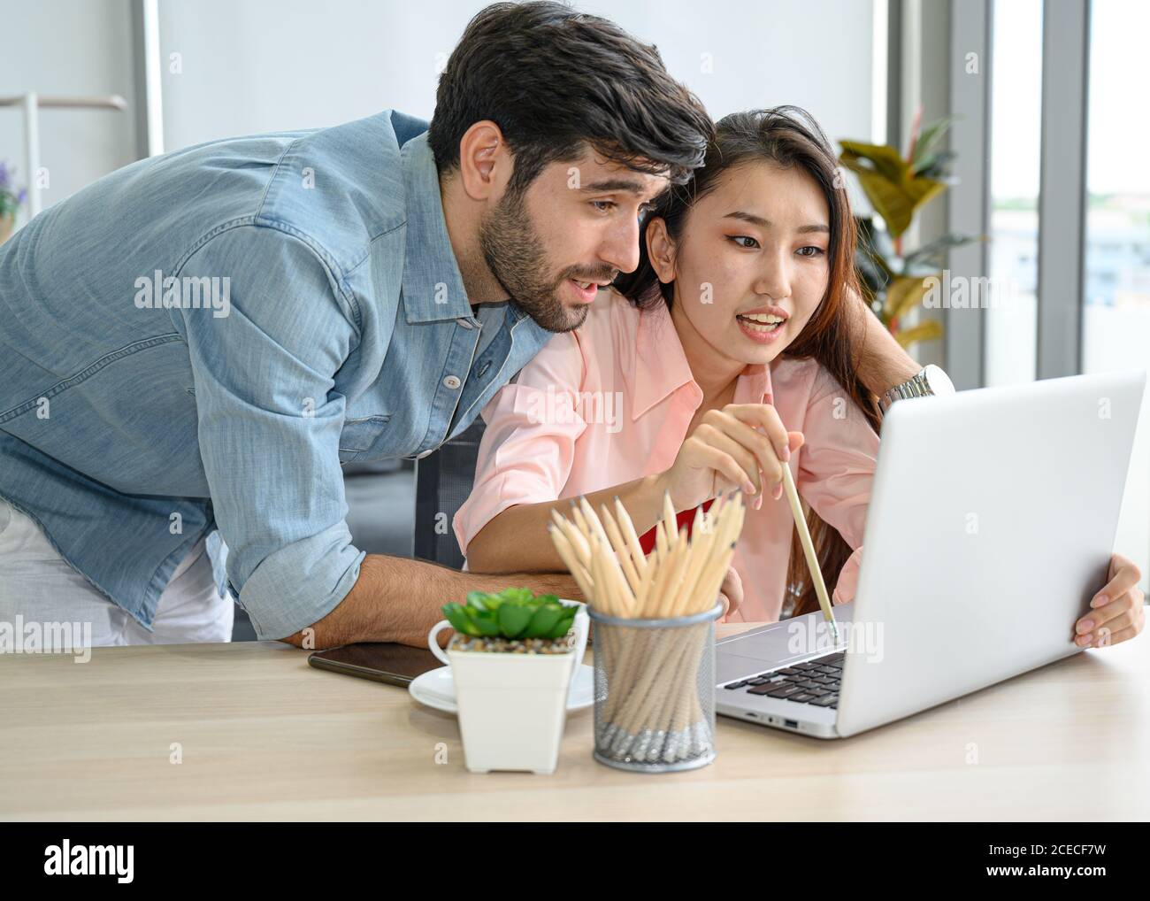 Happy and relax  lifestyle of young couple lover wearing casual dress together working on laptop notebook computer in living room at home. Positive re Stock Photo