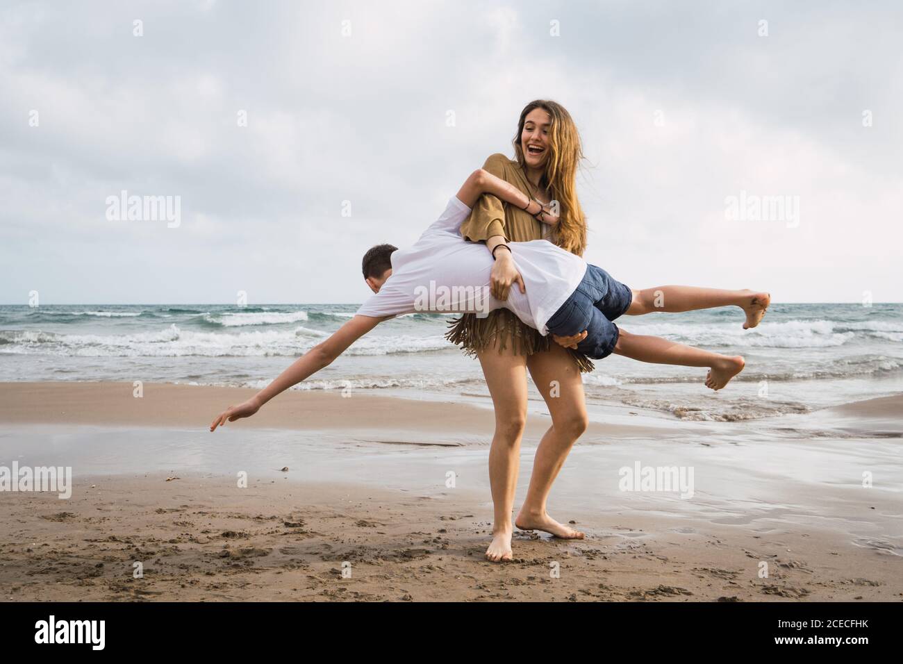 Two laughing young friends fooling around on seashore at summer Stock Photo