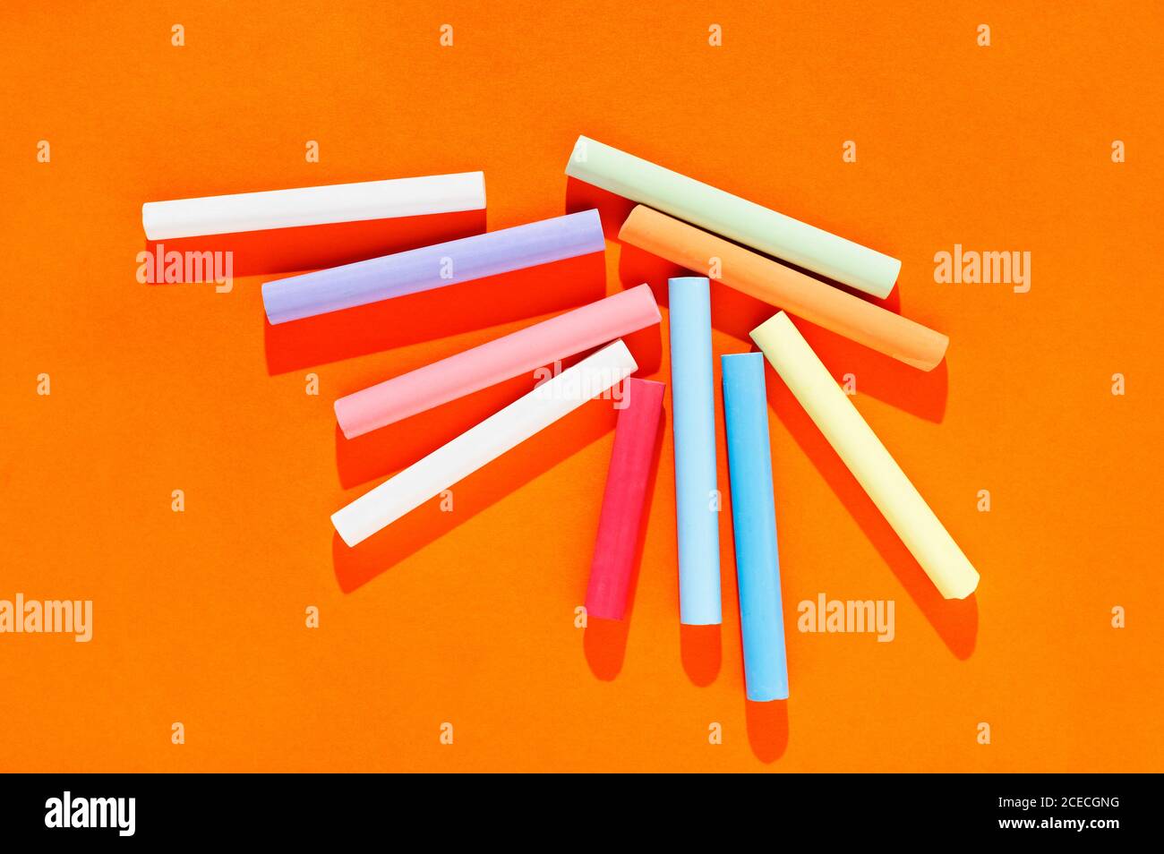 Multicolored thick sticks of chalk on orange background Stock Photo