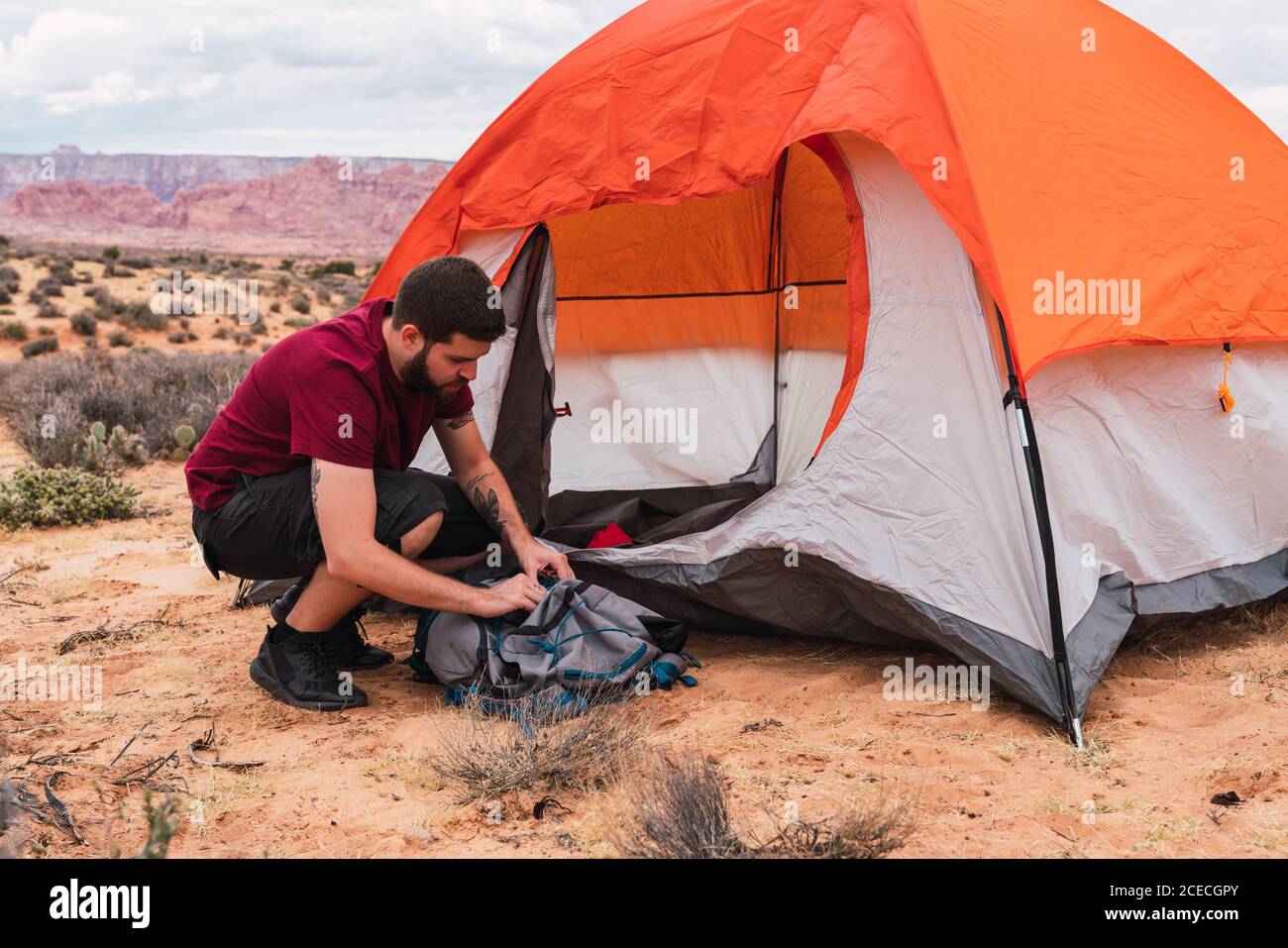 Side view of handsome guy in casual outfit packing backpack while
