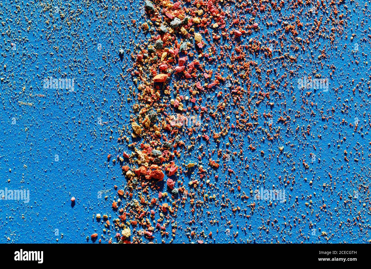 Abstract background of small multicolored pieces of chalk on blue paper Stock Photo
