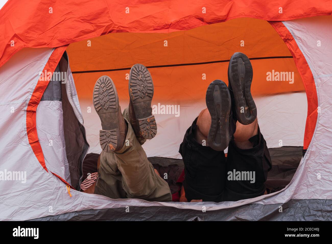 Legs of two male friends lying in modern tent while camping together Stock Photo
