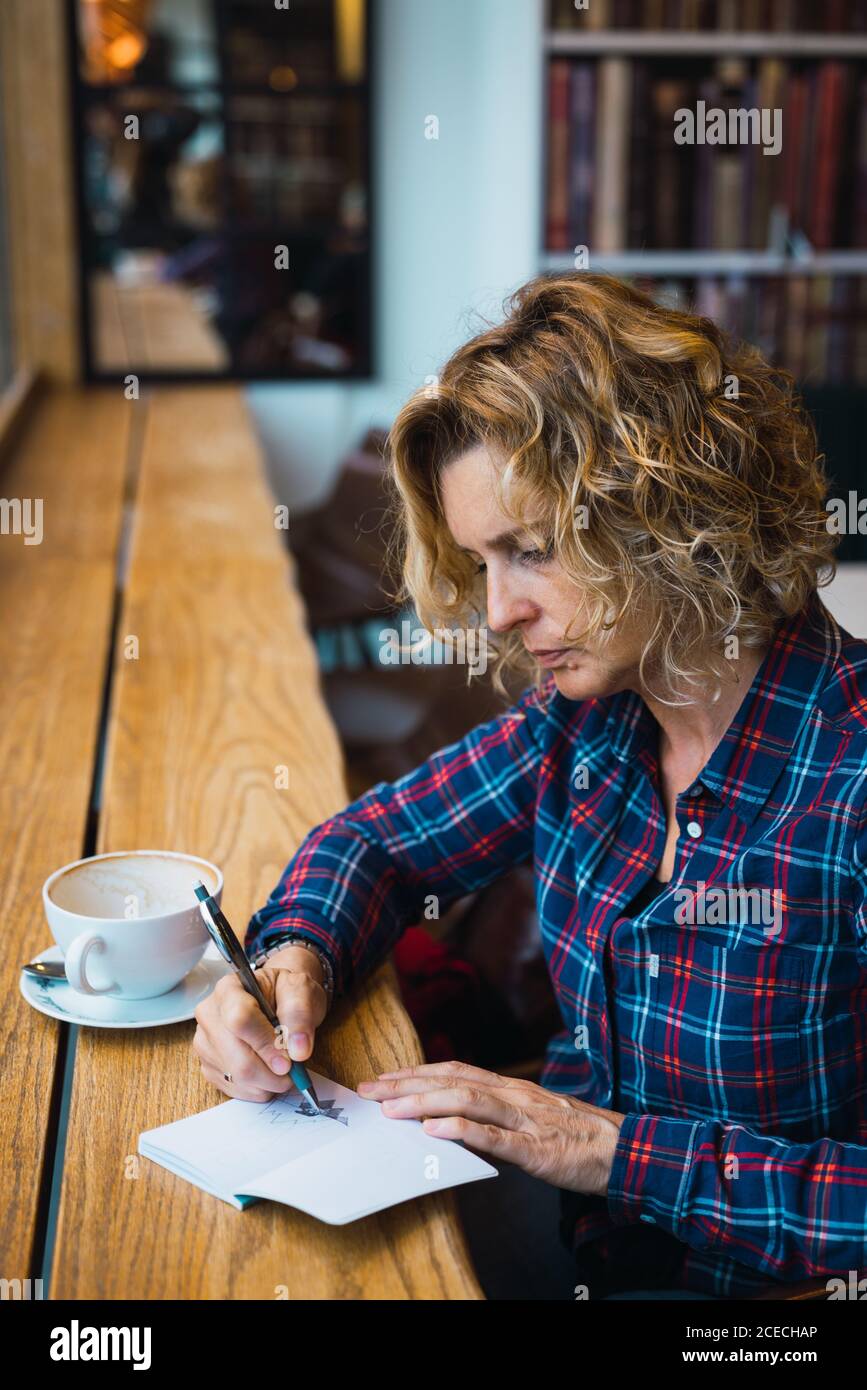 Woman sitting in cafe and writing in notebook Stock Photo