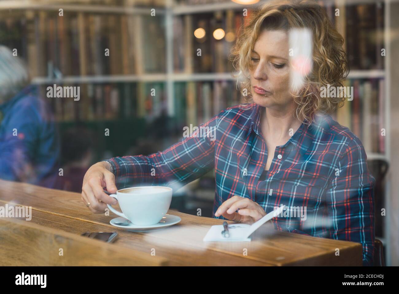Woman sitting in cafe and writing in notebook Stock Photo