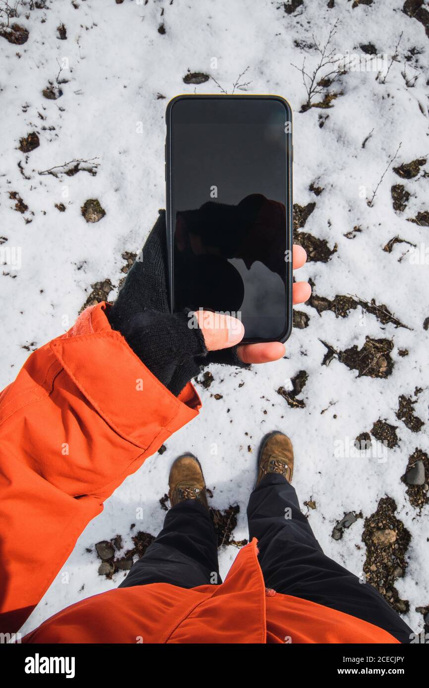 Crop view from above of person holding smartphone outside wearing winter clothes Stock Photo