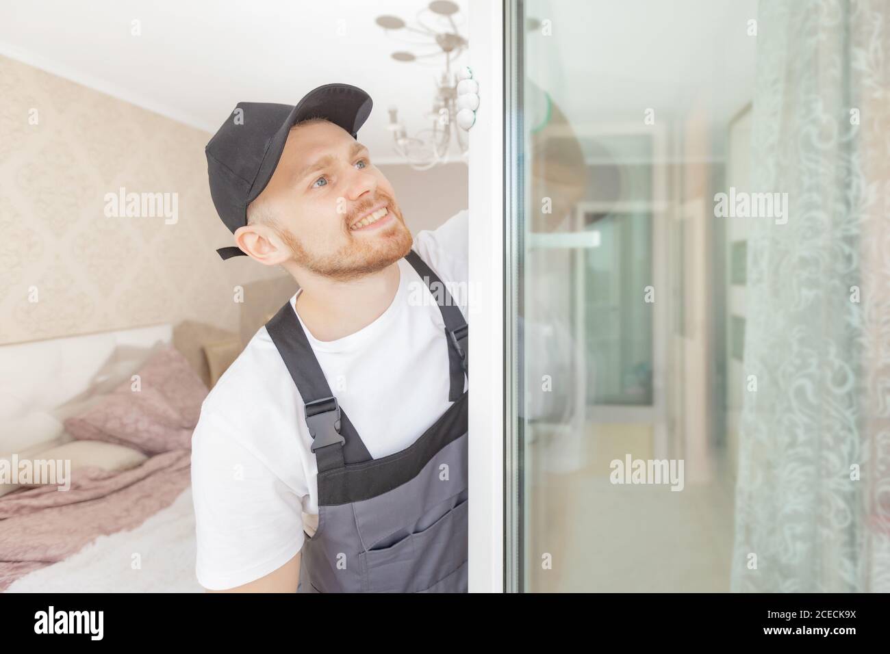 Worker man installs plastic windows white lock and seal adjustment