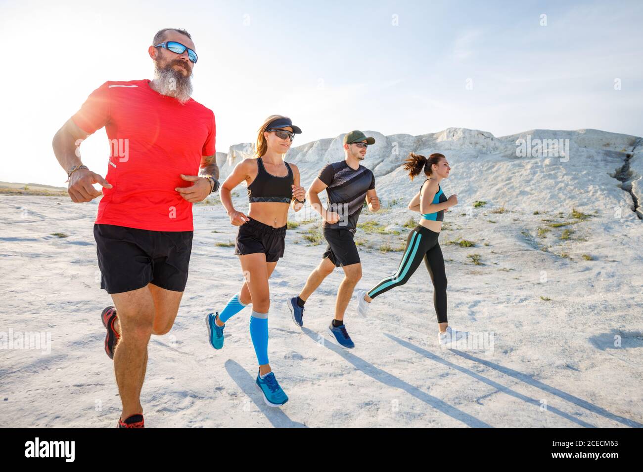 Four fit runners jogging together in desert Stock Photo