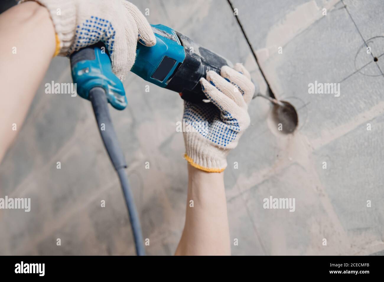 Builder man with pneumatic hammer drill perforator with diamond crown making hole in wall for electric cable, socket, switch Stock Photo
