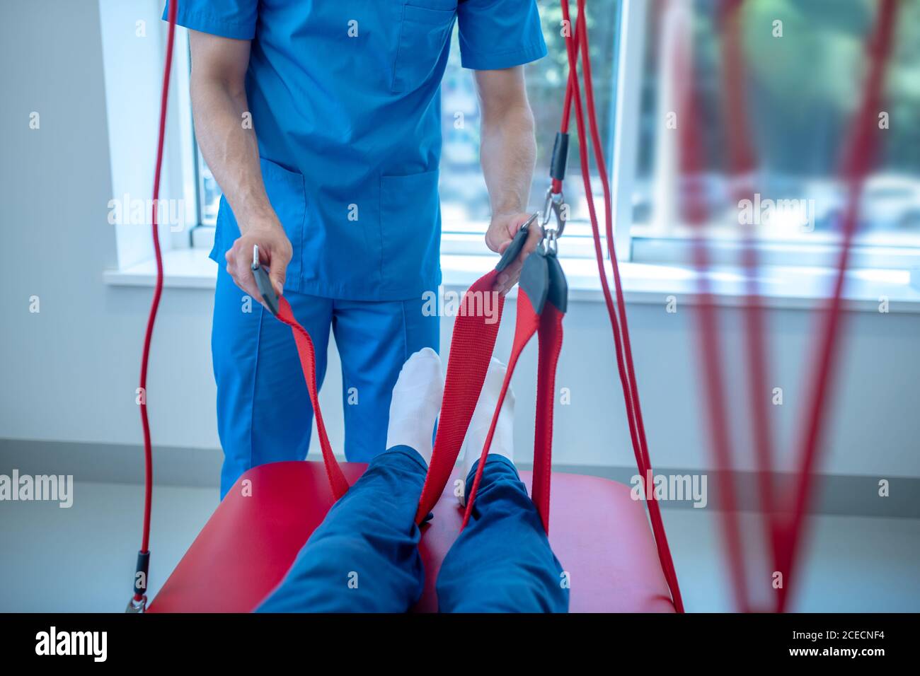 Hands of physician holding belt around patients leg Stock Photo