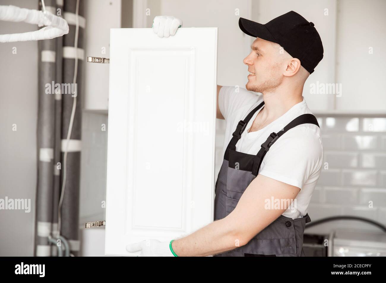 Kitchen installation man. Worker assembling furniture cabinet hinge Stock Photo