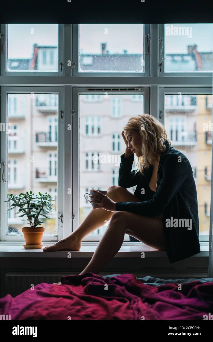 Romantic Woman posing on windowsill Stock Photo