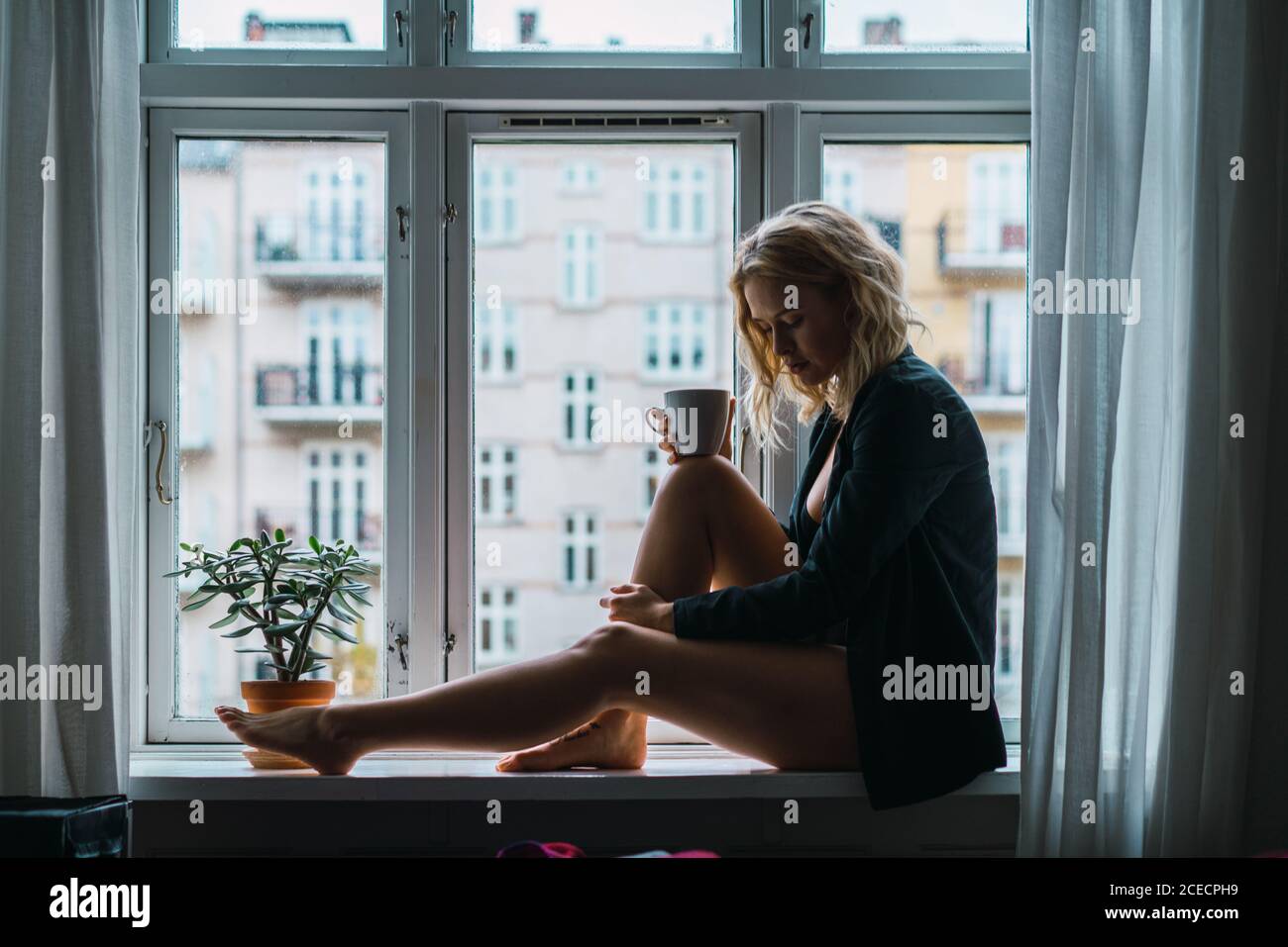 Romantic Woman posing on windowsill Stock Photo