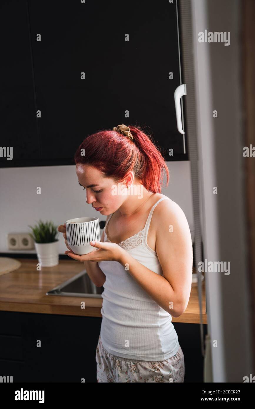 Woman drinking coffee in kitchen Stock Photo
