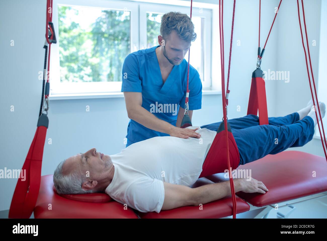 Male doctor touching stomach of lying patient Stock Photo