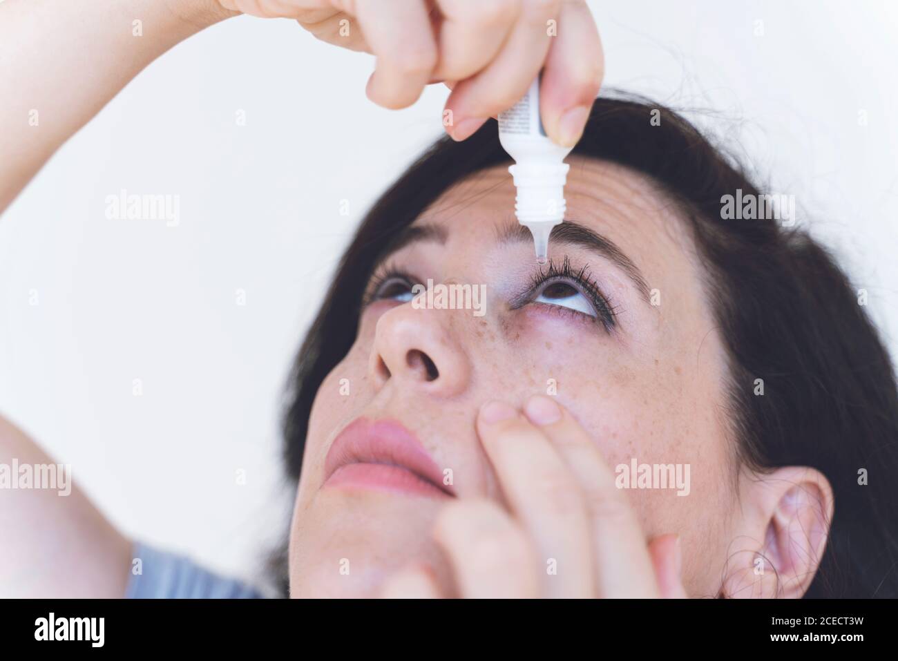 woman using eye drop, woman dropping eye lubricant to treat dry eye or
