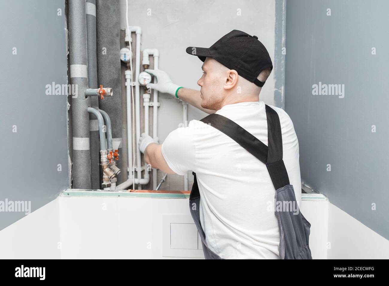 Male plumber checks pipes for central hot and cold water supply of