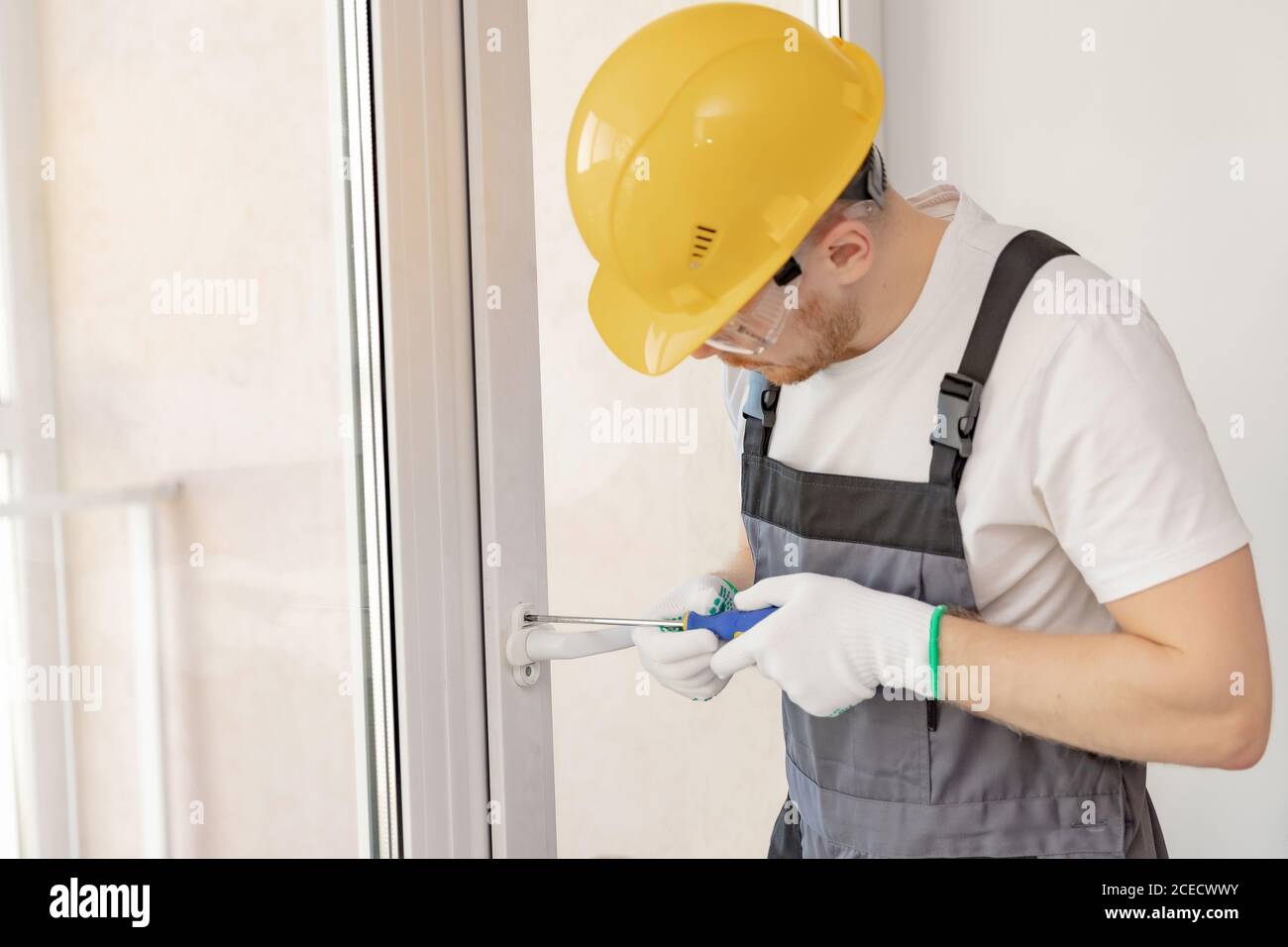 Worker man installs plastic windows white lock and seal adjustment