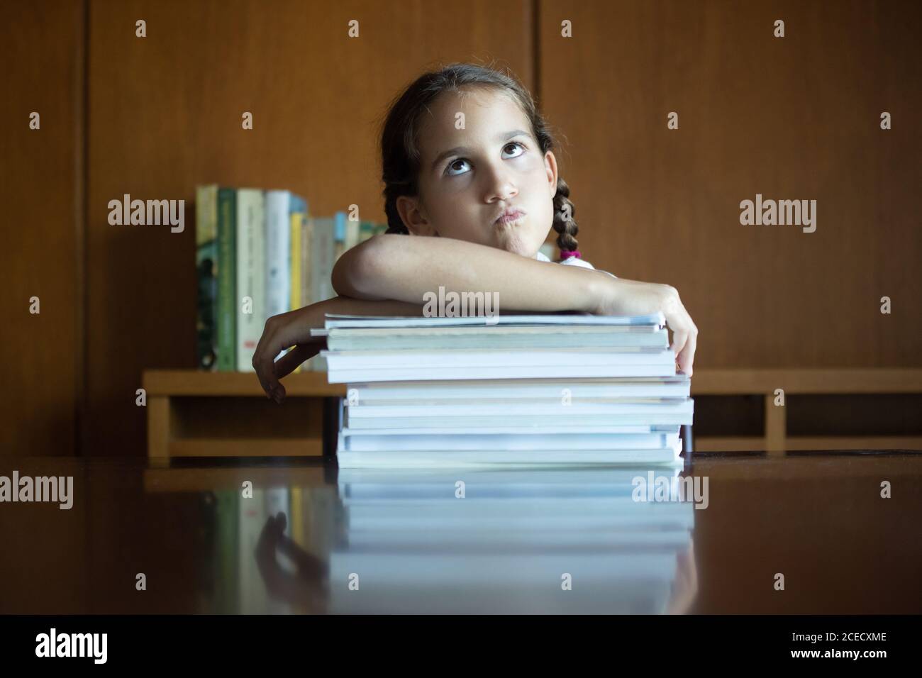 student girl at home unhappy with the amount of homework they have given her at school Stock Photo