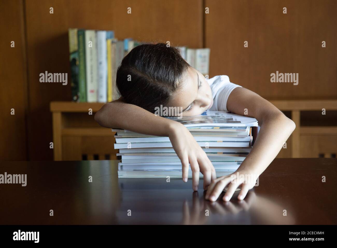 Young student who has fallen asleep on top of textbooks after doing homework for several hours Stock Photo