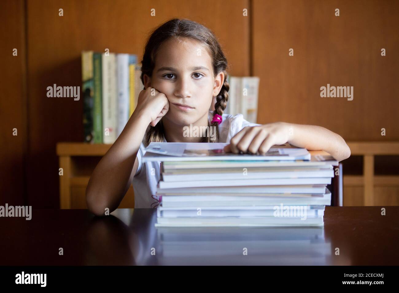 Young student fed up with studying looking towards the camera with her head resting on her hand Stock Photo