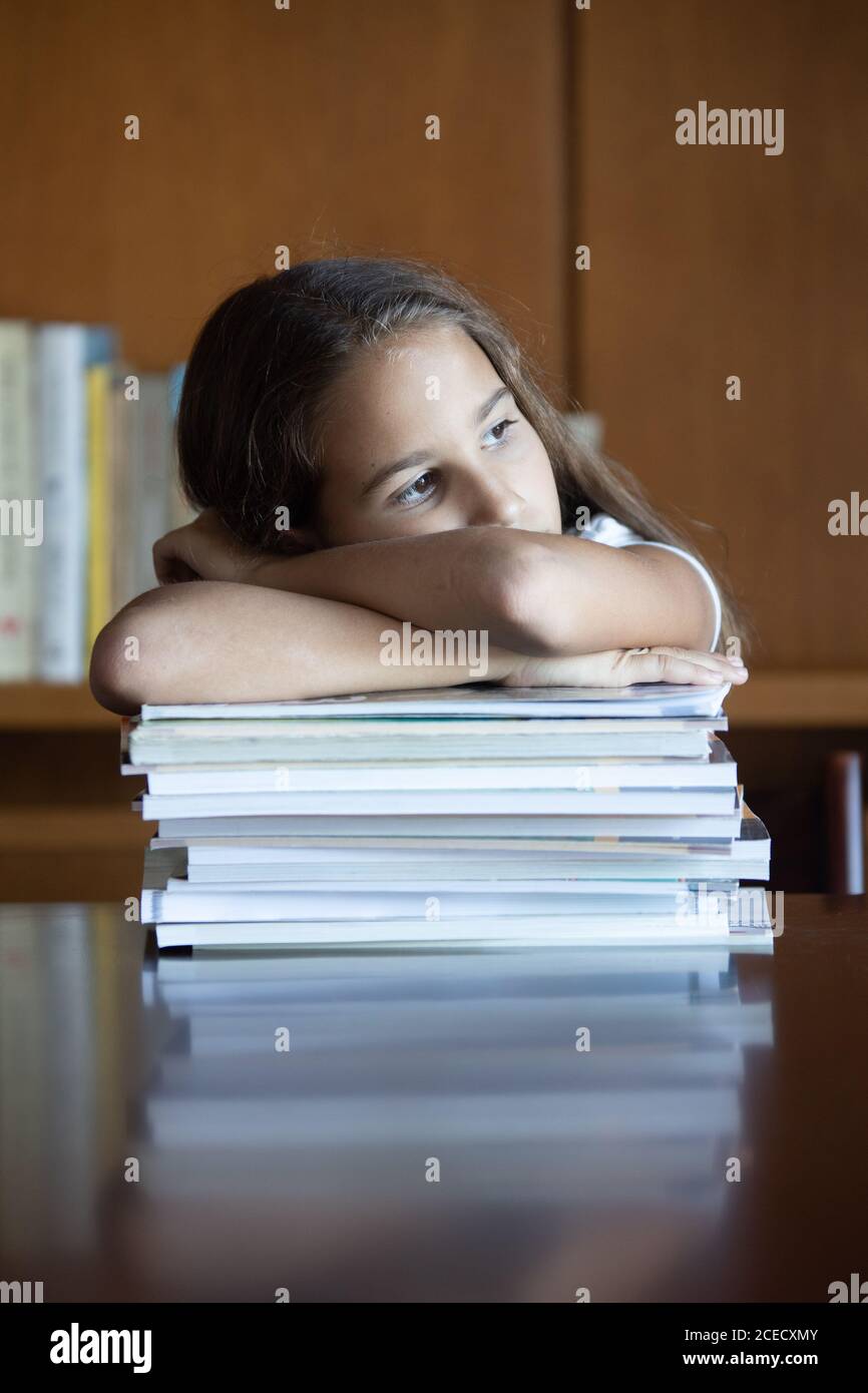 Bored girl leaning on a pile of books staring into infinity Stock Photo