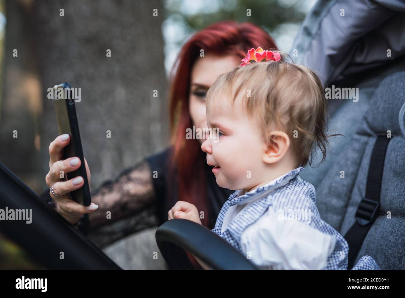 Mother showing smartphone to displeased baby Stock Photo