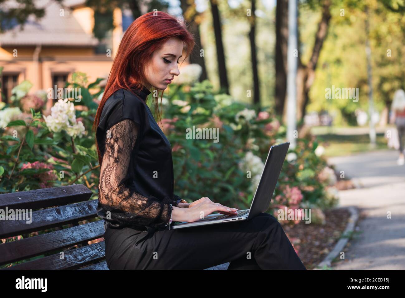 Woman using laptop on bench Stock Photo