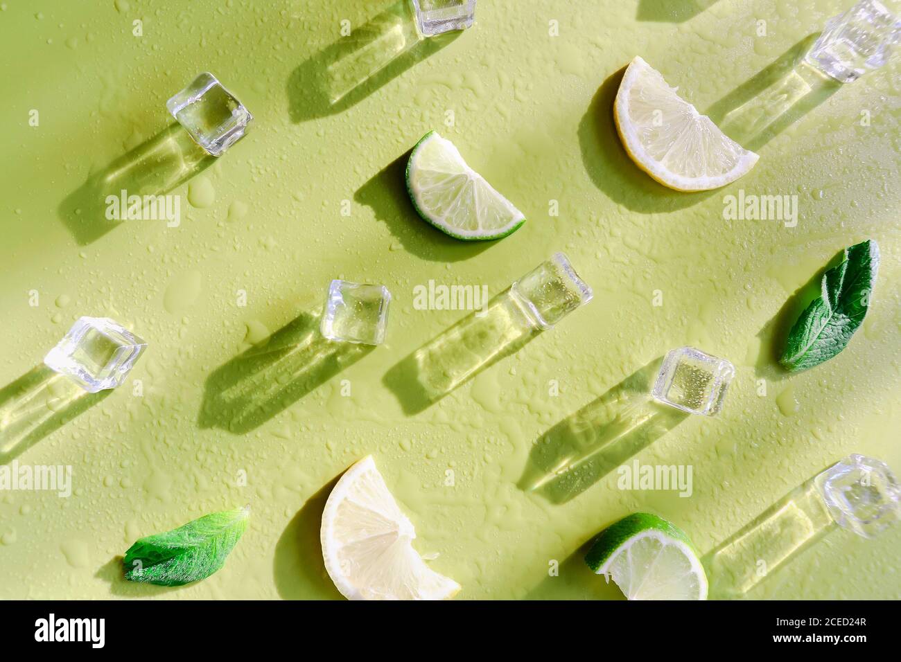 Fresh mint leaf and ice cubes with droplets and lime on green background. Summer background Stock Photo