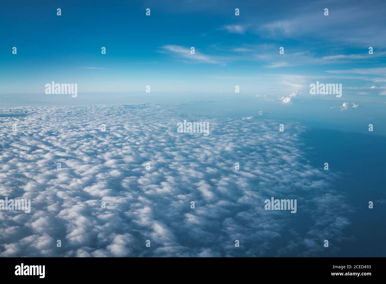Endless view of white clouds below clear blue sky on huge height in sunlight Stock Photo