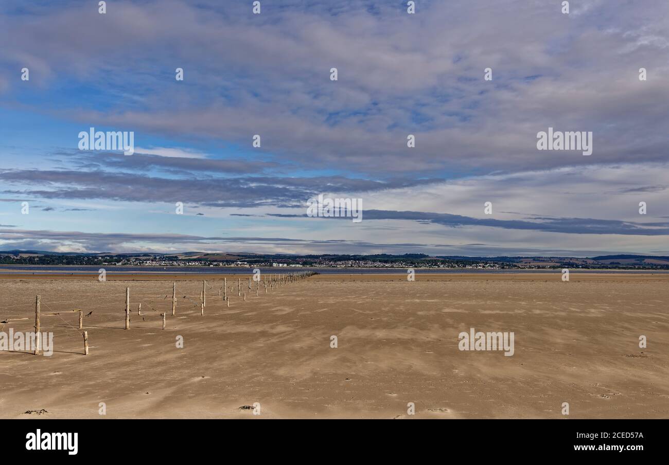 The Wood and Wire fishing Fence line stretching across the Tay Estuary, with Broughty Ferry in the background on the northern shore, under a Big Sky. Stock Photo