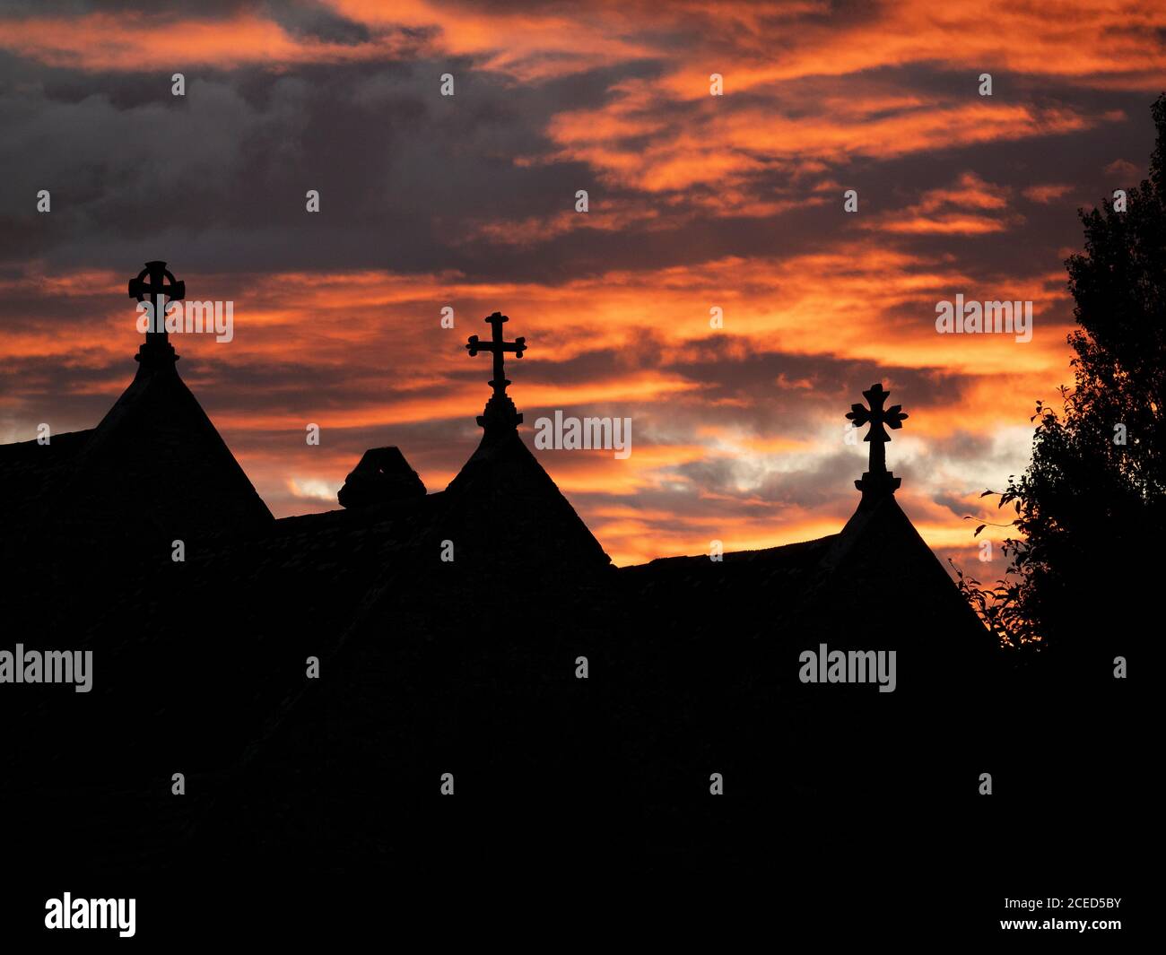 The crosses of St Bartholomew's church in Shapwick, Dorset, UK, silhouetted against the glowing sunset sky. Stock Photo